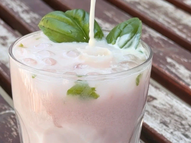 Raspberry basil cream soda in a tall glass garnished with fresh basil