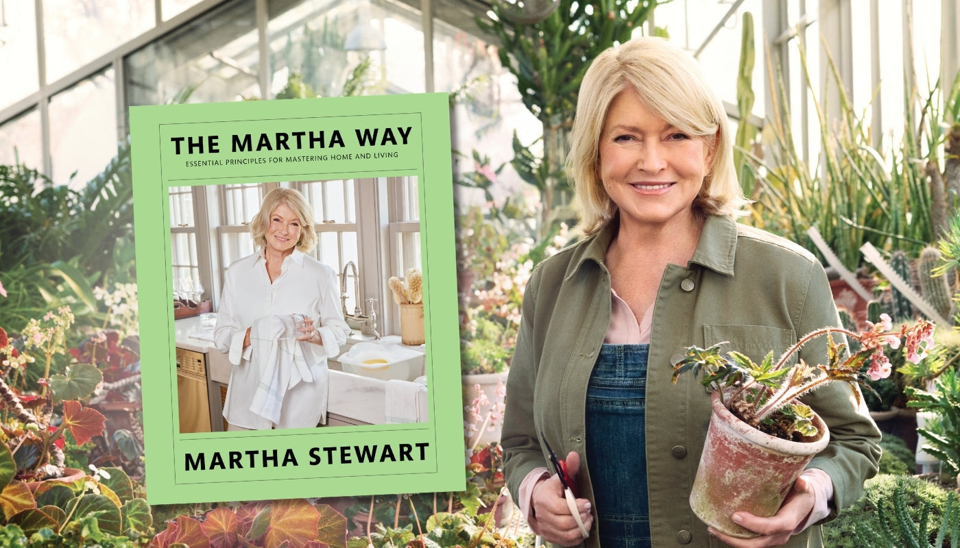Woman holding a plant in a greenhouse with a book titled 'The Martha Way' by Martha Stewart.