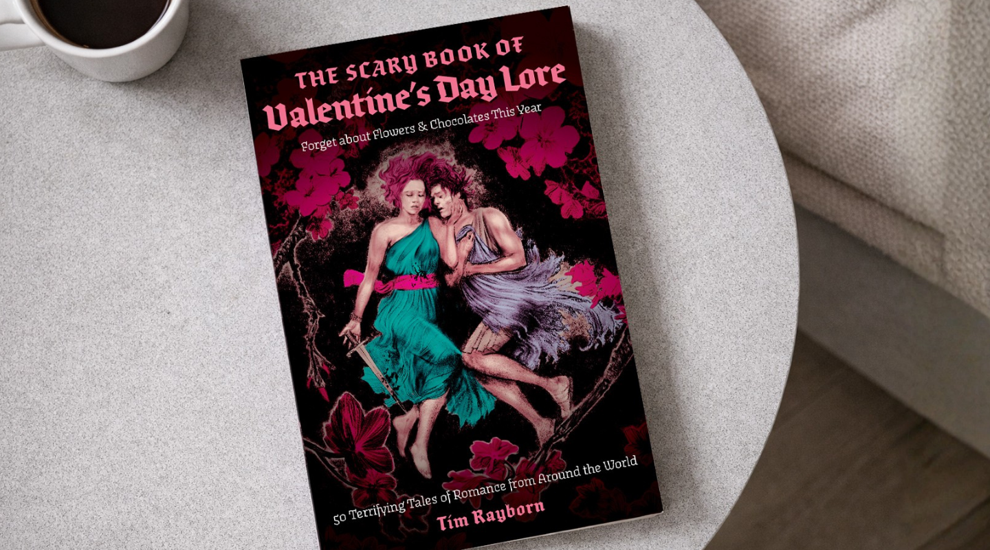 Book titled 'The Scary Book of Valentine's Day Love' on a table with a cup of coffee.